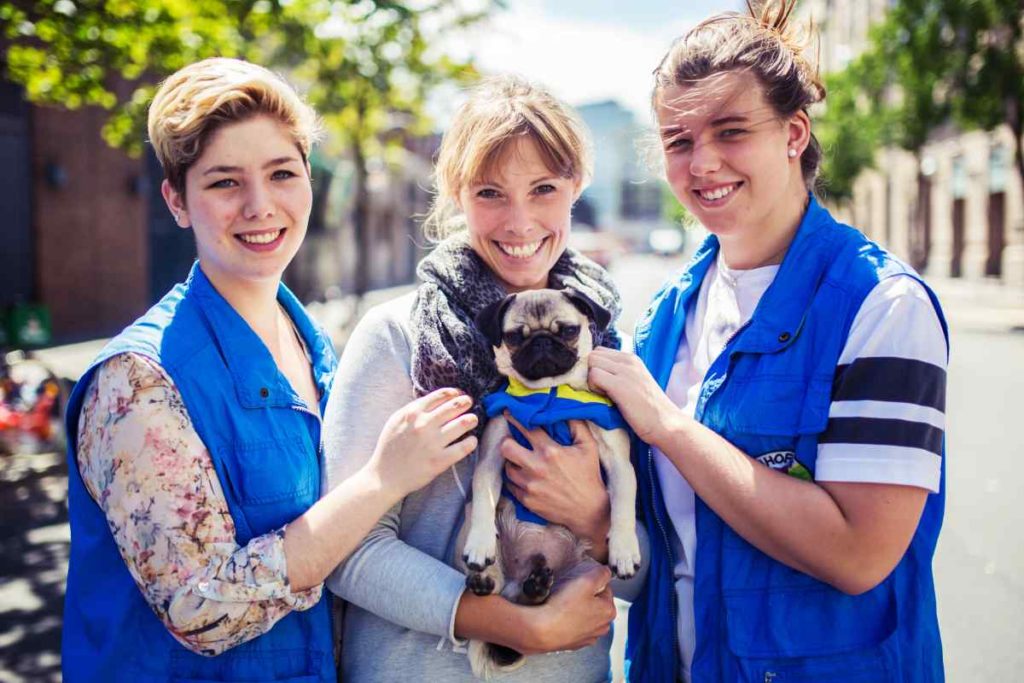 Die Mitarbeiterinnen der Bahnhofsmission, Jasmin (l-r), Claudia und Carolin posieren mit dem Mops Arnold in Berlin.